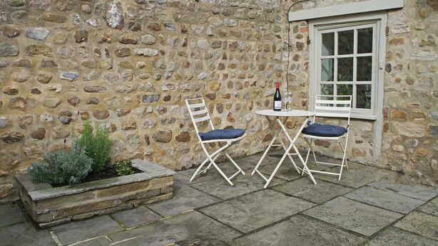 A stone wall with a window and a small table with two chairs. - Country Hideaways | The Hay Loft | Ripon (Ripon)