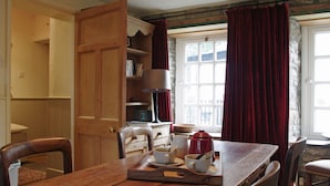 A wooden dining table with a tray holding cups and a teapot, a wooden chair, and a bookshelf with books. - Country Hideaways | The Old Wheelhouse | West Burton (Leyburn)