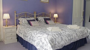Een slaapkamer met een hemelbed, twee nachtkastjes en een deur.