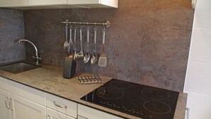 Una cocina moderna con un lavamanos de acero inoxidable, una placa de cocina empotrada y un colgador para utensilios.