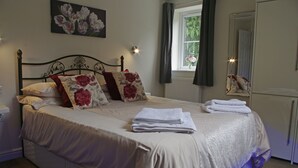 Un lit bien fait, agrémenté de coussins à motifs floraux, une lampe de chevet et une fenêtre avec des rideaux.