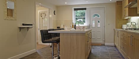 A modern kitchen with a central island, wooden cabinets, and a bar stool.