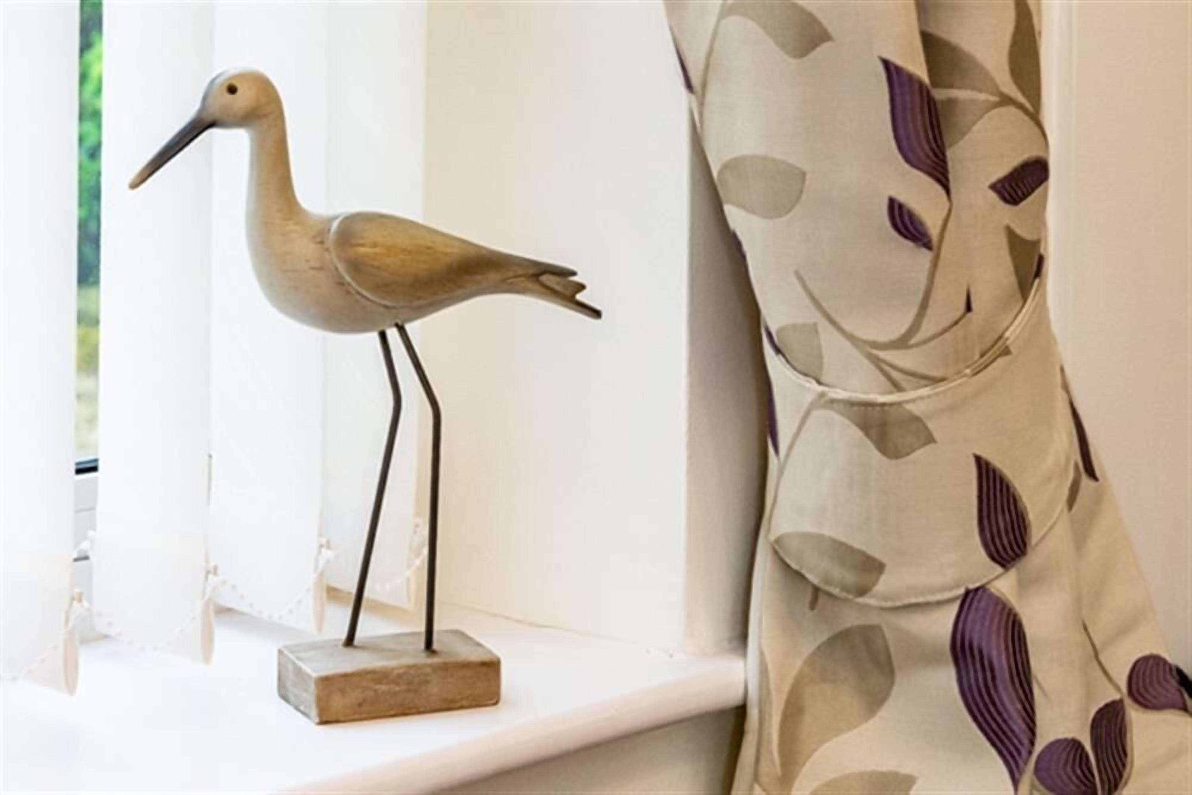 Una escultura con forma de pájaro en un alféizar.