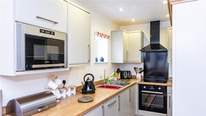 A compact kitchen with a microwave, kettle, toaster, and oven.
