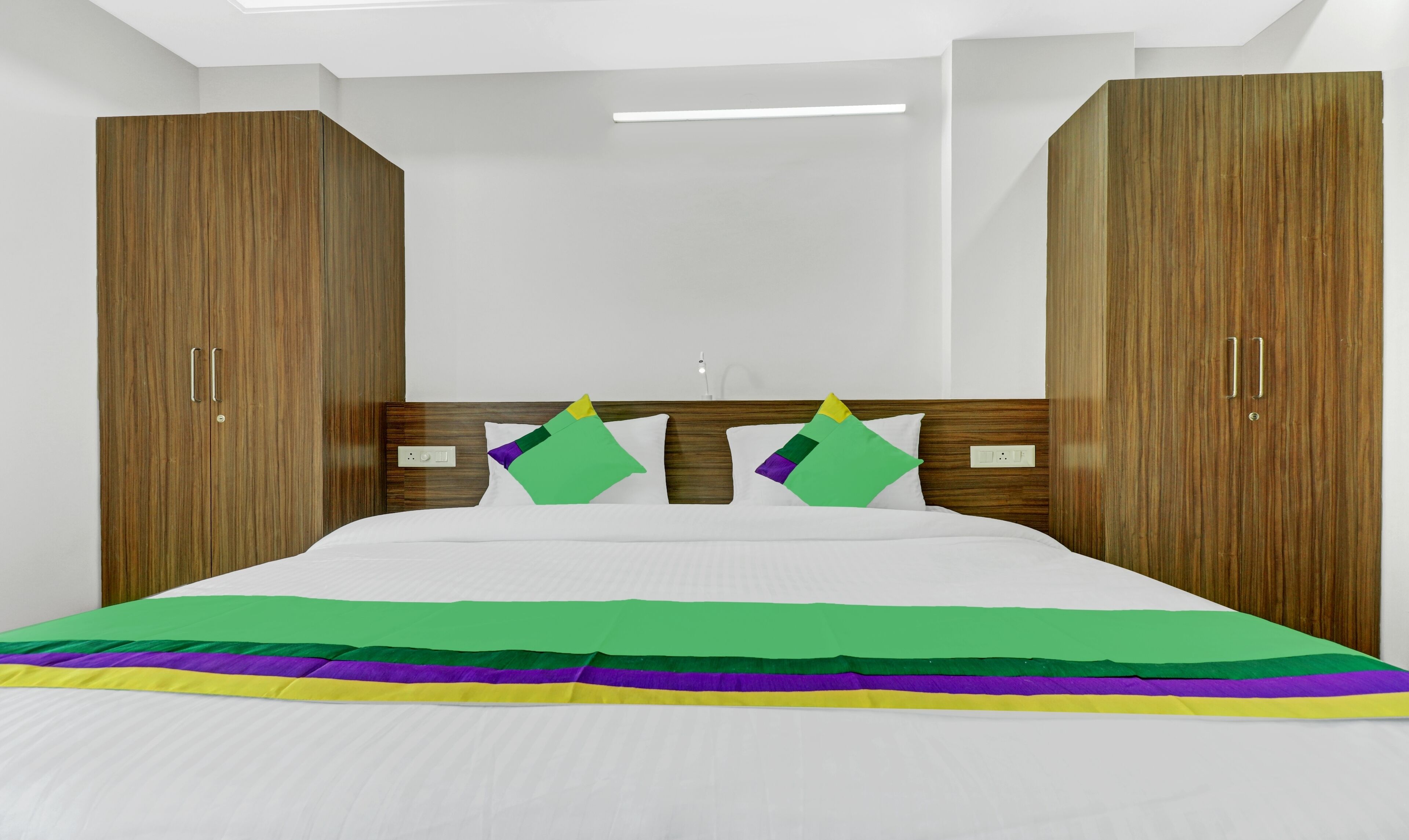 A hotel room with a bed, wooden wardrobe, and a night light.