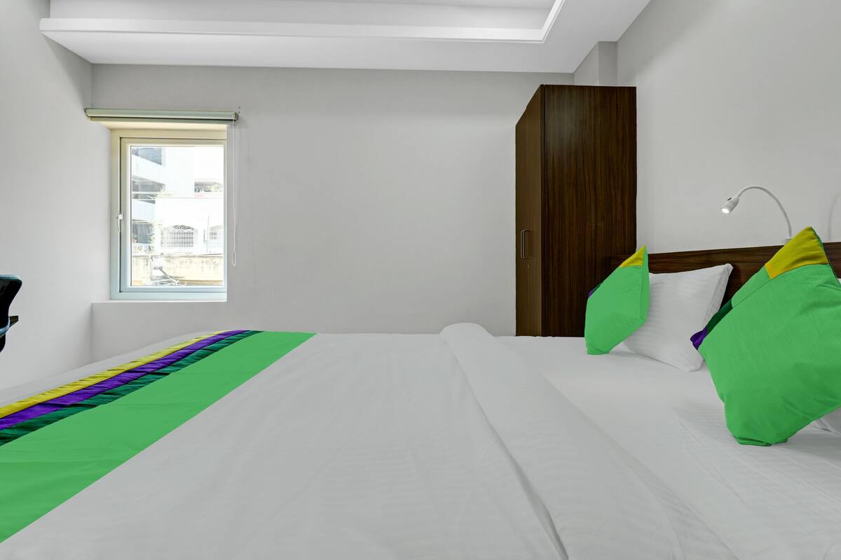 A hotel room with a bed, a window, a wardrobe, and a desk.
