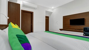 A hotel room with a bed, a TV mounted on the wall, and a wooden door. - Treebo Raga (Visakhapatnam)