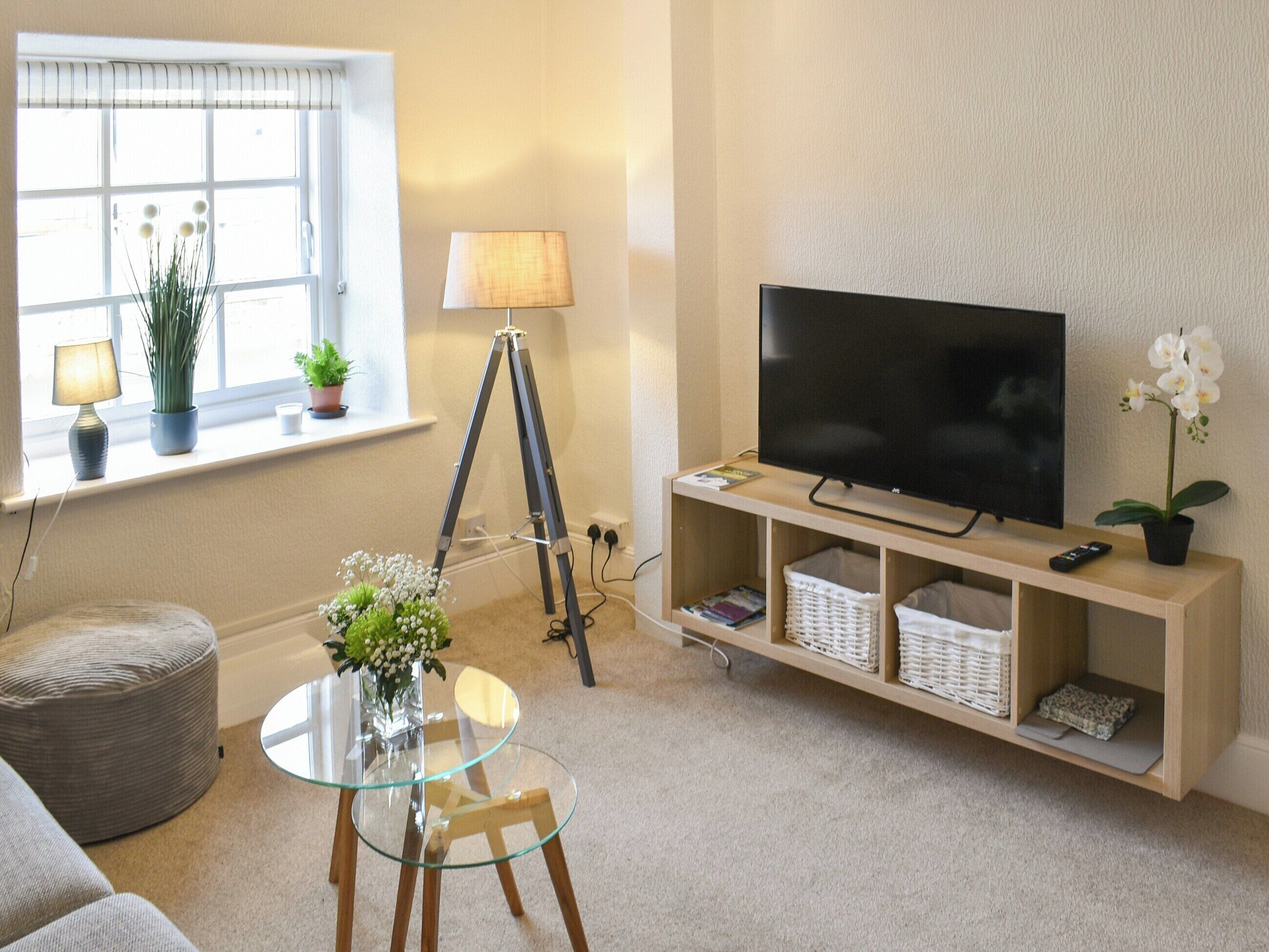 A living room with a TV, a tripod, a lamp, a glass table, and a sofa.