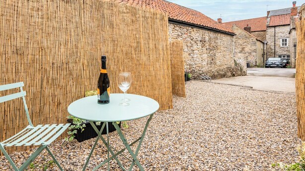 A small outdoor seating area with a table, a chair, a bottle of wine, and a glass. - 1 bedroom accommodation in Helmsley (Helmsley)