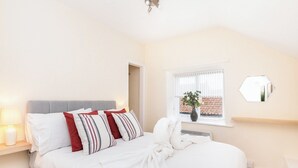 A bedroom with a bed, bedside table, lamp, window, and a wall-mounted mirror. - 1 bedroom accommodation in Helmsley (Helmsley)