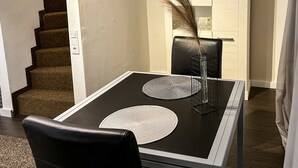 A dining area with a black table, two white placemats, a black chair, and a vase with dried plants. - Apartelliment bianco-nero - modern accommodation in Cologne (Köln)