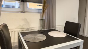 A modern dining area with a black table, two white placemats, a black lamp, and a vase with dried plants. - Apartelliment bianco-nero - modern accommodation in Cologne (Köln)