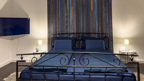 A modern bedroom with a metal bed frame, two bedside tables with lamps, and a large TV mounted on the wall. - Apartelliment bianco-nero - modern accommodation in Cologne (Köln)