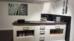 A modern kitchen with a laptop, a coffee machine, and a zebra print artwork on the wall. - Apartelliment bianco-nero - modern accommodation in Cologne (Köln)