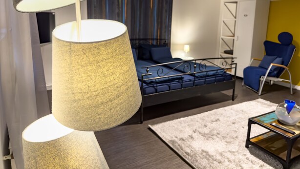 A modern bedroom with a bed, a chair, a lamp, and a small table. - Apartelliment bianco-nero - modern accommodation in Cologne (Köln)