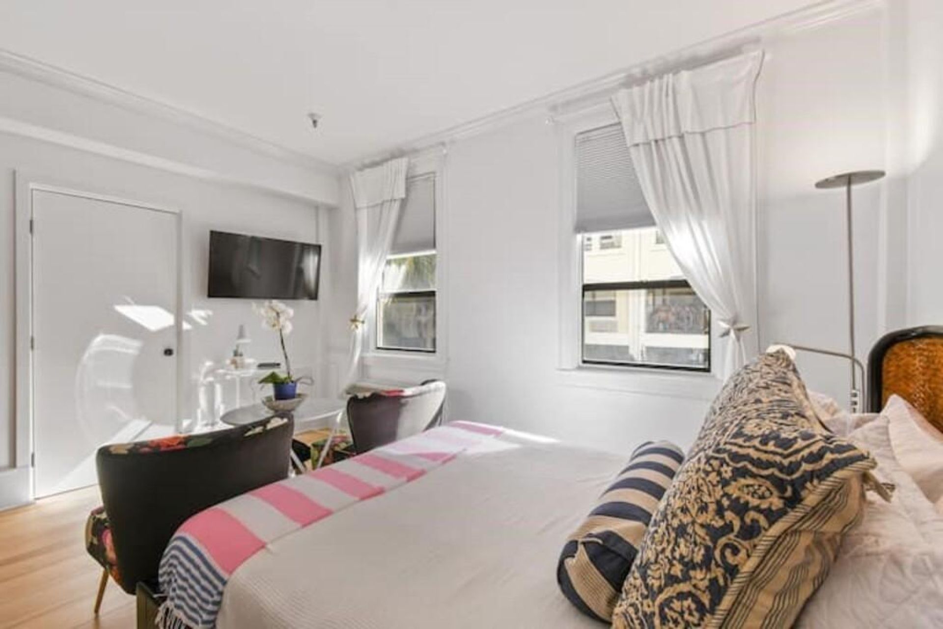 A bedroom with a bed, a desk, a chair, and a television on the wall.
