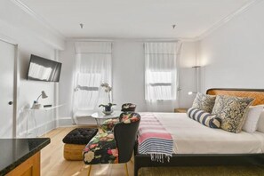 Ein Schlafzimmer mit einem Bett, einem Schreibtisch, einem Sessel und einem Fernseher.