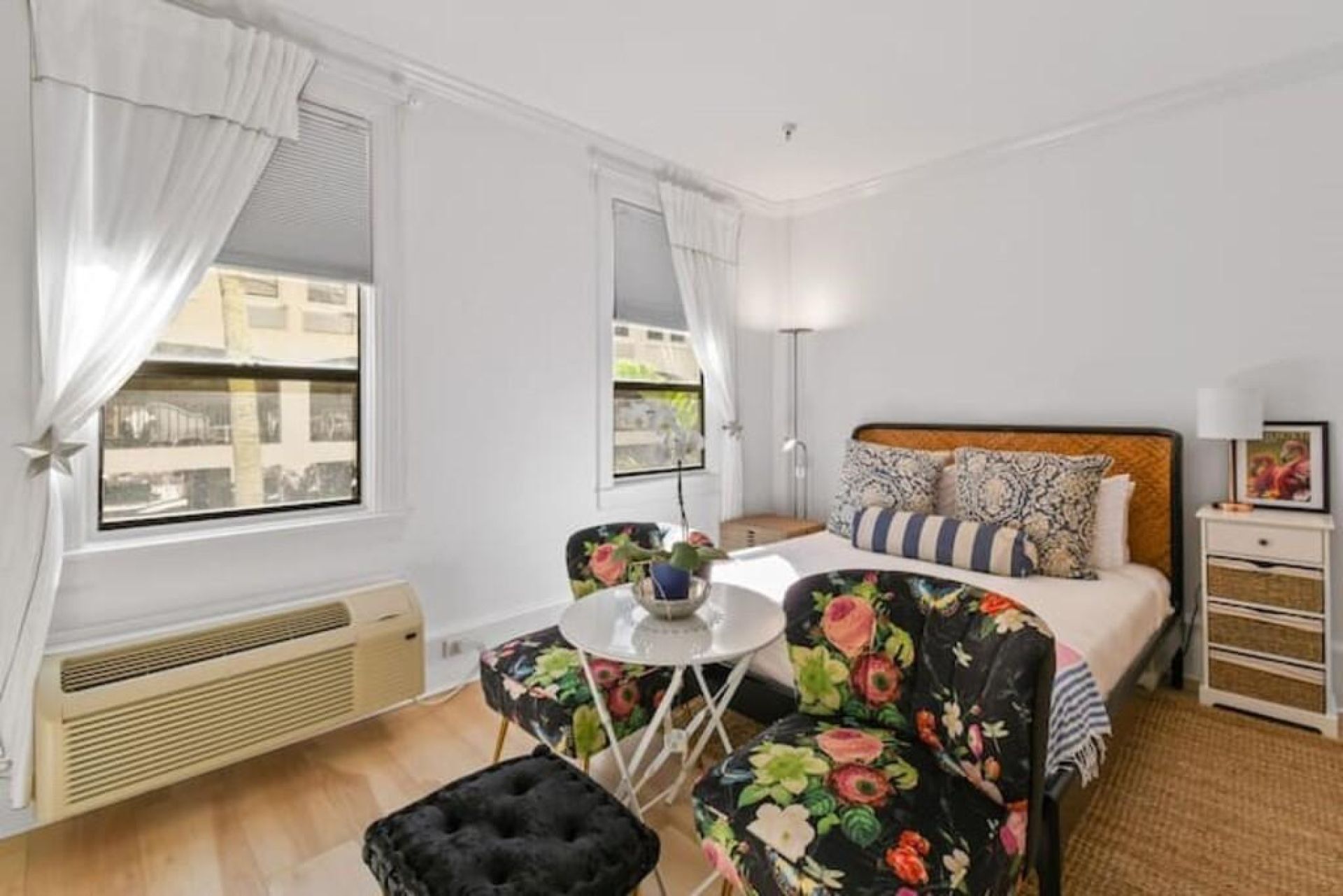 A bedroom with a bed, a small table, a chair, and a radiator.