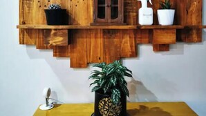 A wall-mounted wooden shelf unit with various items including a potted plant, a spray bottle, and decorative objects.