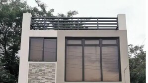 A modern two-story house with a flat roof, large windows, and a small front porch.