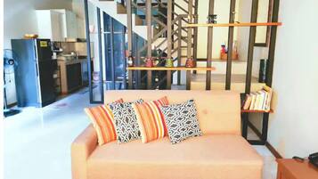 Relax in this stylish living room with a sofa, bookshelf, and staircase, perfect for unwinding.