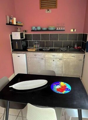 A compact kitchen with a black countertop, a microwave, a small refrigerator, and a sink. - 3- Moringa (La Trinité)