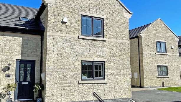 A two-story building with a stone facade, a dark-colored door with the number 5, and a small window with a curtain. - 3 bedroom accommodation in Buxton (Buxton)