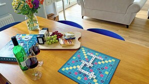 A dining table with a Scrabble board, a bottle of wine, and a vase of flowers. - 3 bedroom accommodation in Buxton (Buxton)