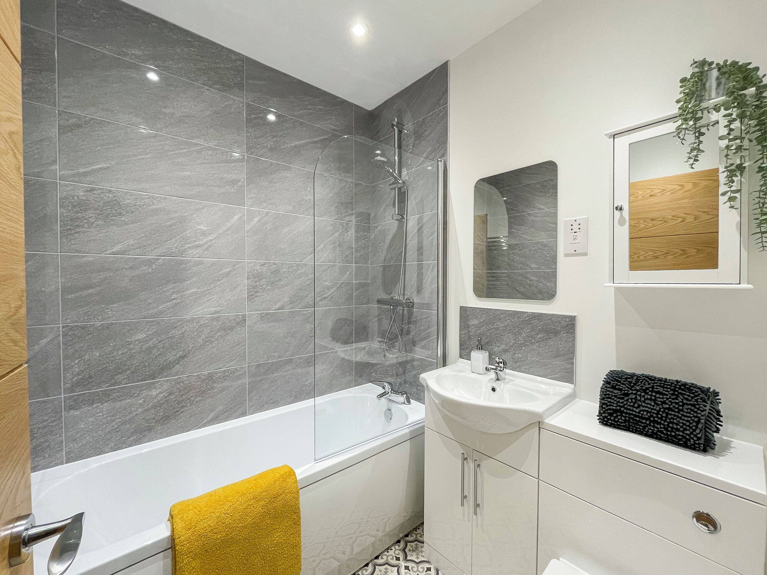 Ein modernes Badezimmer mit Badewanne, Dusche und Waschbecken, mit Marmorfliesen und einem Holzbadezimmerkorpus.
