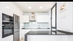 Una cucina moderna con mobili bianchi, un piano di lavoro nero ed elettrodomestici in acciaio inossidabile.