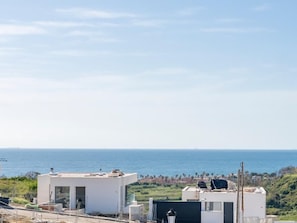 Blick auf die Küste mit modernen Gebäuden, blauem Himmel und dem Meer im Hintergrund.