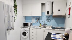 A compact kitchen with a washing machine, microwave, and stove. - Paradise By The Sea - TheWhaleBeachHouse (Atouguia da Baleia)
