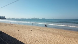 A sandy beach with people walking along the shore and a clear view of the ocean. - Condos Ventana R (Mazatlán)