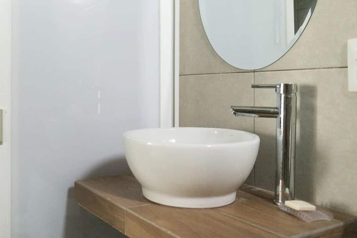 Un baño con lavamanos blanco, espejo y encimera de madera.