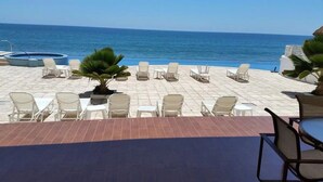 A terrace with white lounge chairs and a small pool, overlooking the ocean. - Condos Ventana R (Mazatlán)