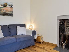 A living room with a sofa, a lamp, a fireplace, and a painting on the wall. - Full of character, this cosy cottage is in a quiet lane in a charming village. (Perth)
