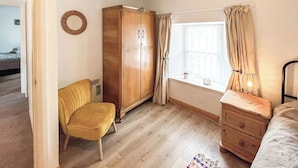 A room with a wardrobe, a chair, a window with curtains, a dresser, and a radiator. - Full of character, this cosy cottage is in a quiet lane in a charming village. (Perth)