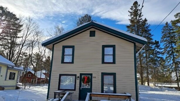 A two-story house with a front porch and steps leading to the door. - Stay near Mirror Lake, enjoy our cozy 2-bedroom cottage (Lake Placid)
