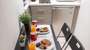 A compact kitchen with a dining table, chairs, a microwave, and a coffee machine. - Byronico Acropolis Apartment by MPS (Αθήνα)