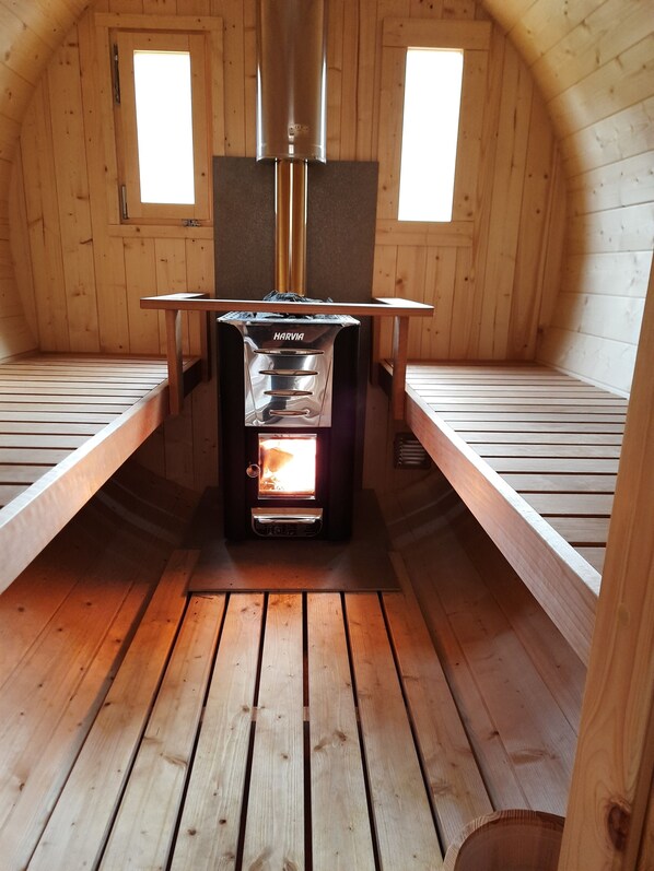 Une cabane chaleureuse avec un poêle à bois, des murs en bois et un plafond en pente.