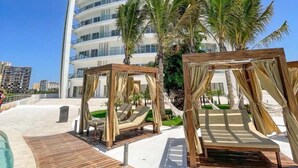 Un complexe hôtelier moderne doté d’un bâtiment aux lignes courbes, d’une terrasse en bois et de palmiers.