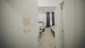 A hotel corridor with a bed, a sofa, and a desk. - Dimora Fantasia Charme B&B (Bari)