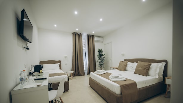 A modern hotel room with a bed, desk, chair, and a TV mounted on the wall. - Dimora Fantasia Charme B&B (Bari)