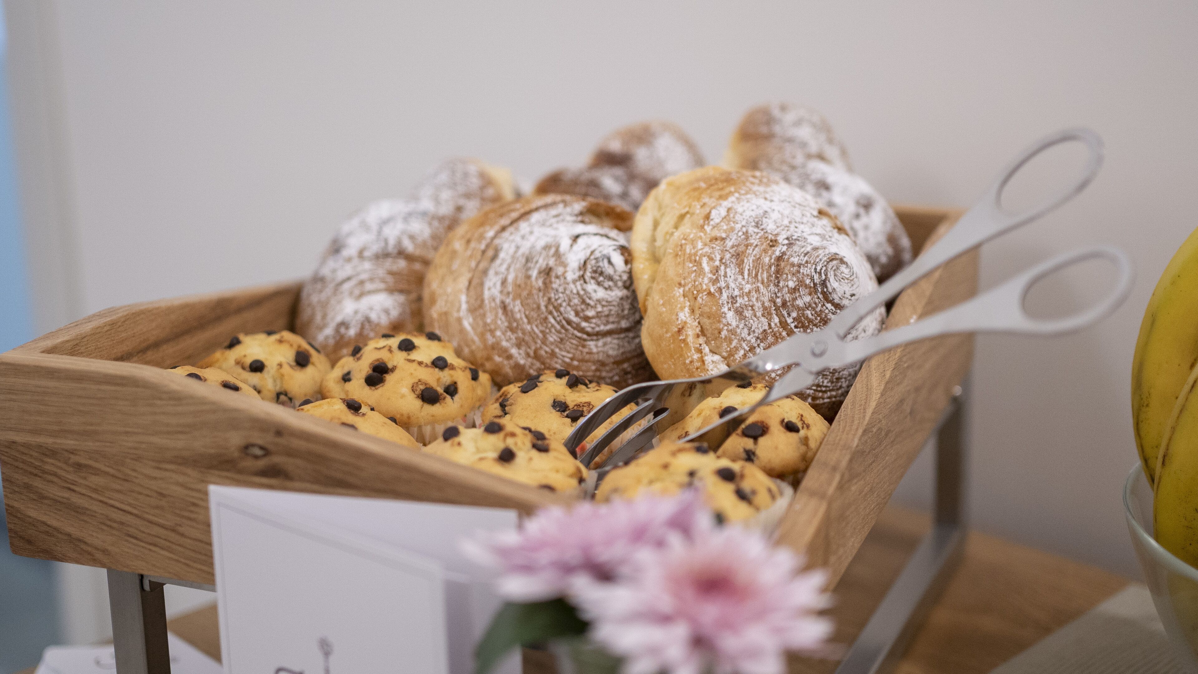 Puiselle alustalle on aseteltu erilaisia leivonnaisia ja keksejä, ja sen vieressä on saksipari sekä kukka.