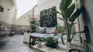 A cozy outdoor seating area with a sofa and chairs, surrounded by potted plants and a decorative wall. - Dimora Fantasia Charme B&B (Bari)