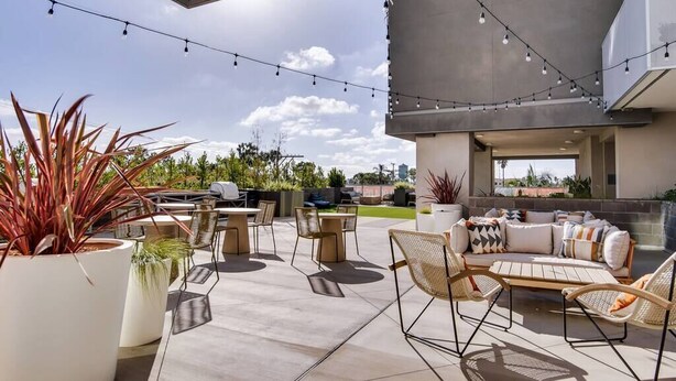 An outdoor patio area with seating, potted plants, and string lights.