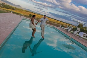 Une piscine offrant une vue dégagée sur le paysage environnant, notamment sur un vignoble et des montagnes lointaines.