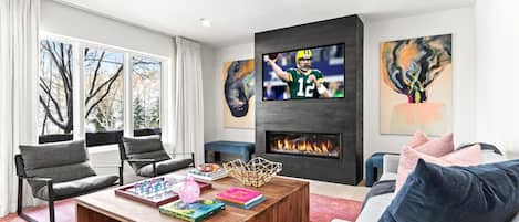 Una sala de estar moderna con chimenea, televisor y obras de arte en las paredes.