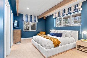 A bedroom with a large bed, a wooden dresser, and a window with a view of trees. - Park City | KBM Resorts | Indoor Pool,Home Theater, Playground | Single Unit, 6 Bedrooms |  ML-618 (Park City)
