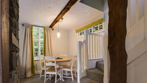 A dining area with a table and chairs, a staircase, and a window with curtains.